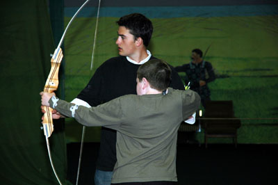 Young boy being taught archery by young man